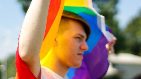 A man holding up a gay pride flag.