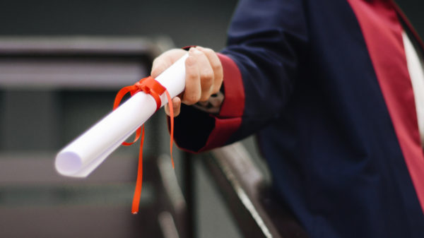 College student handing out a paper rapped in a ribbon