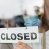 closed sign on business and woman with mask.