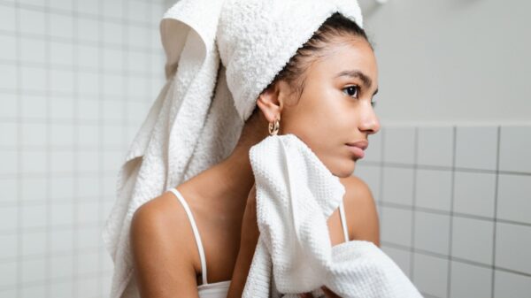 girl with clear skin rubbing her face with a towel.