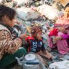 A mother and her children eat among discarded materials.