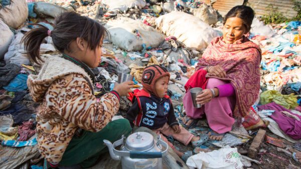 A mother and her children eat among discarded materials.