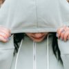 Girl holding her hood over her head while looking down.