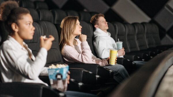 Group of people sitting in a movie theater eating popcorn.