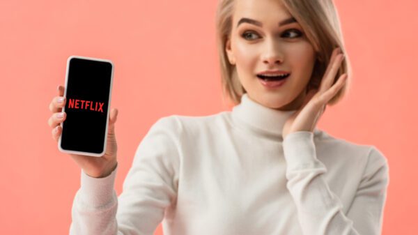 Woman stares at cell phone that says "Netflix" on it.
