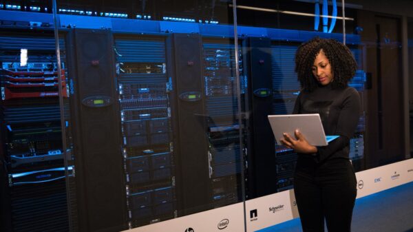 Software engineer standing beside server racks.
