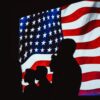Silhouettes of people in front of a flag.