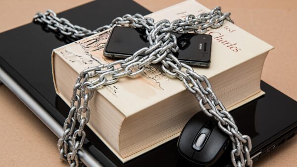 A smartphone, book, and laptop chained together.,