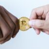Two people holding a Bitcoin.