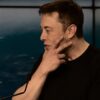 Elon Musk touching his face.