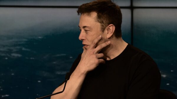 Elon Musk touching his face.