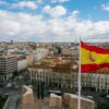 A Spanish flag in front of buildings.