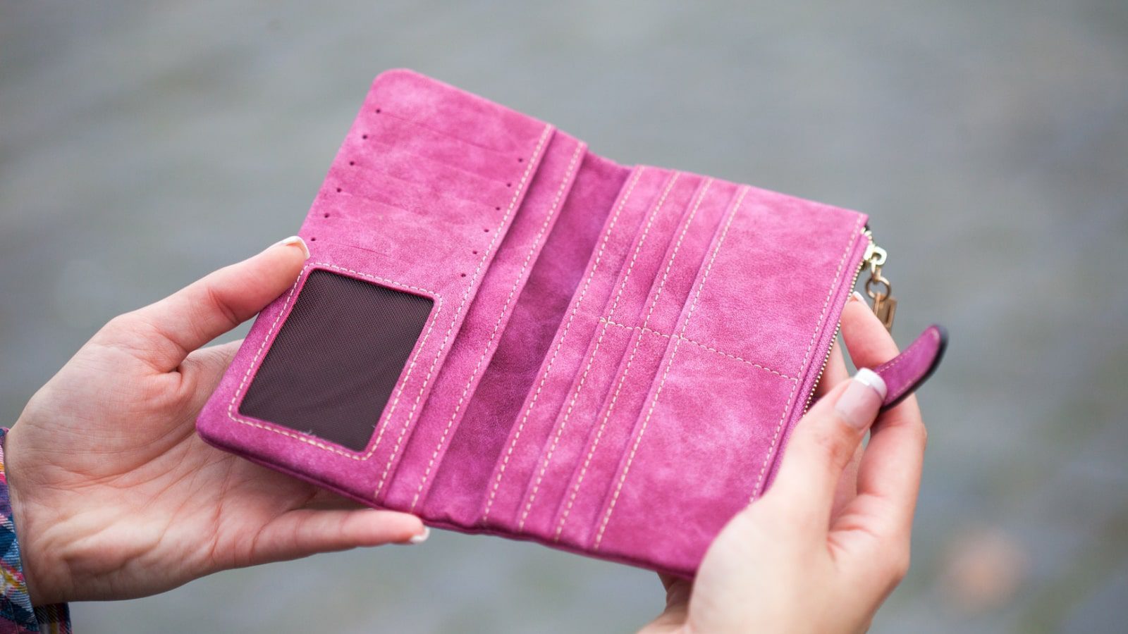 A person holding a pink suede wallet.
