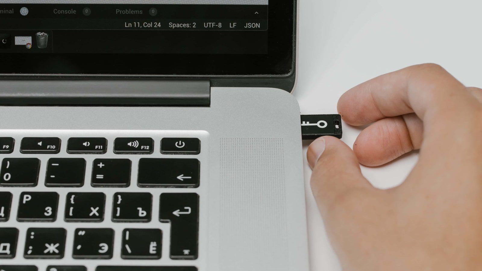 A hand removing a USB drive from a laptop.