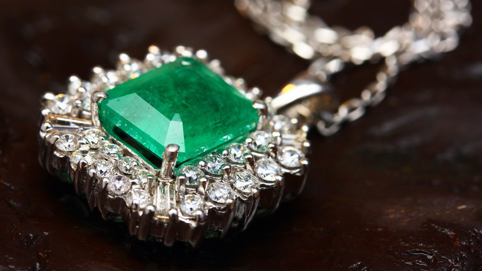 A diamond-encrusted pendant with a large green gemstone.