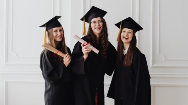 Three college graduates wearing caps and gowns.