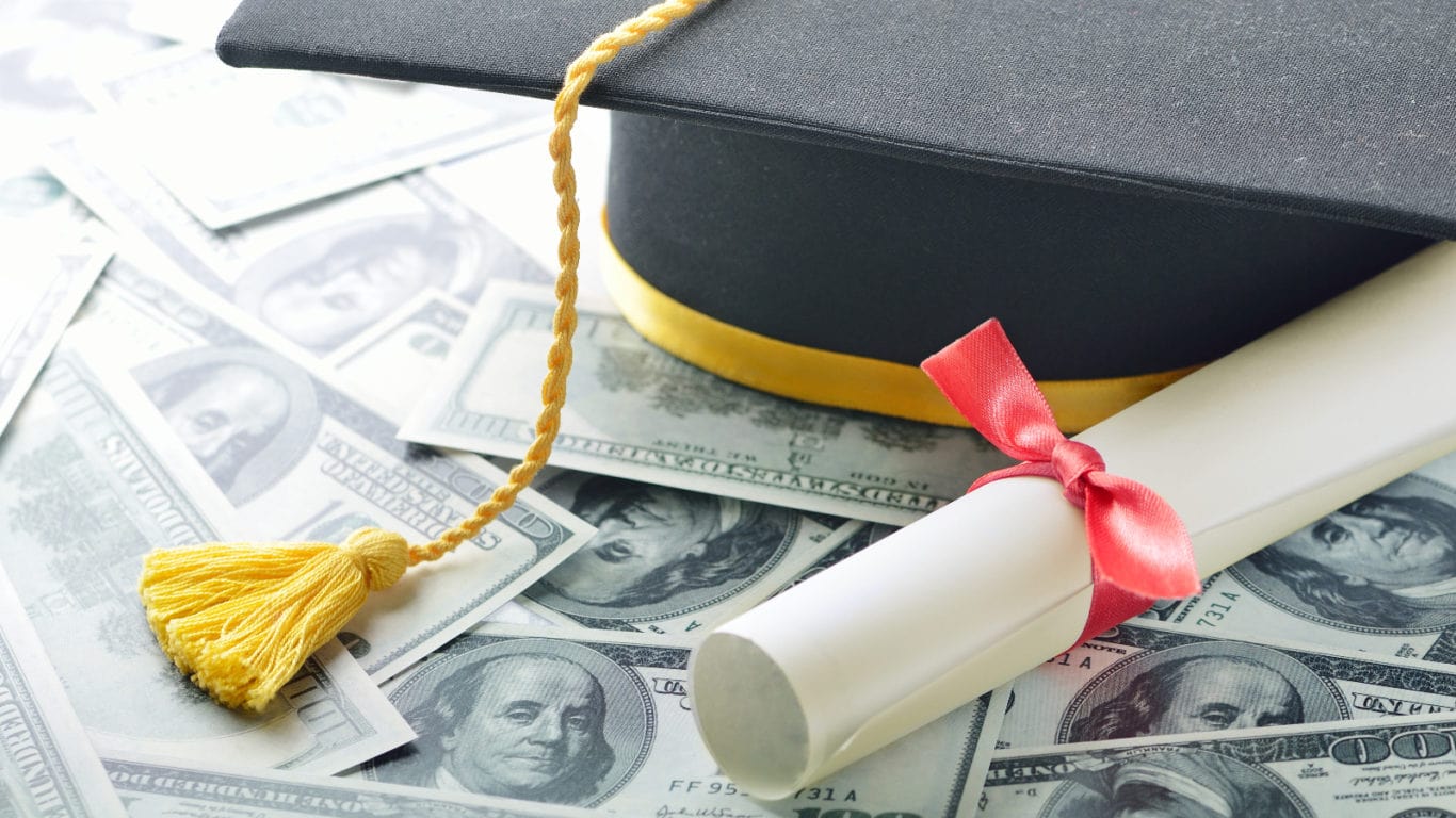 A graduation cap and diploma on top of cash.