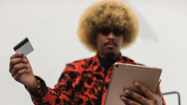 A man holding a card looking at a tablet.