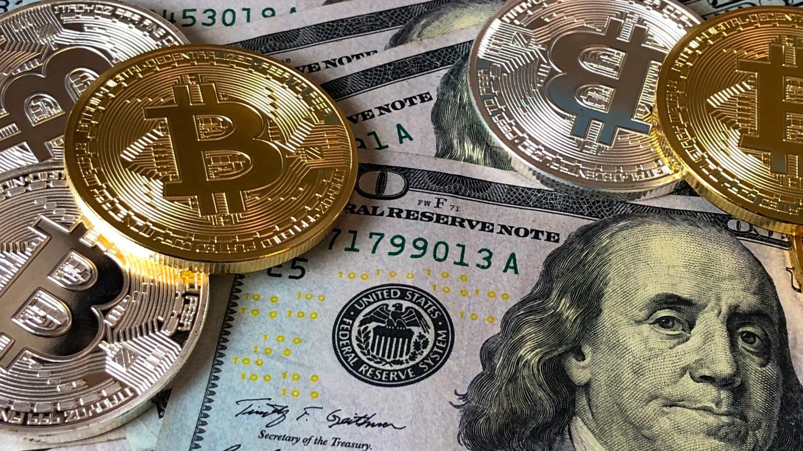 Bitcoins on top of hundred dollar bills.