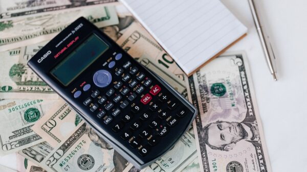 A calculator and notepad on top of cash.