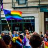 A crowd holding up a rainbow flag.