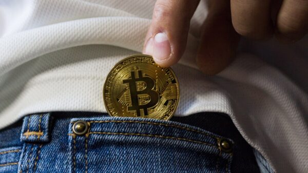 A person putting a golden Bitcoin in their pocket.
