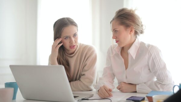 Two women talking in front of a laptop.