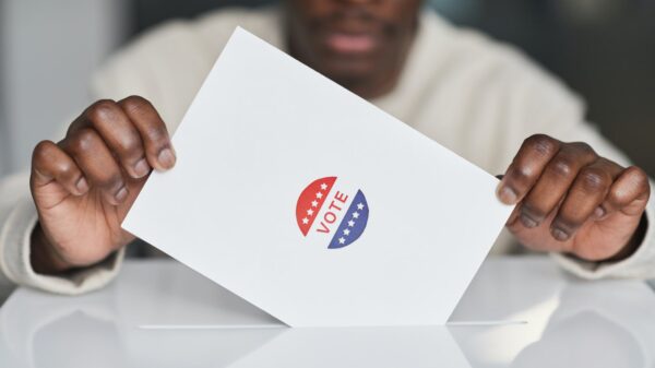 A person putting a paper in a ballot box.