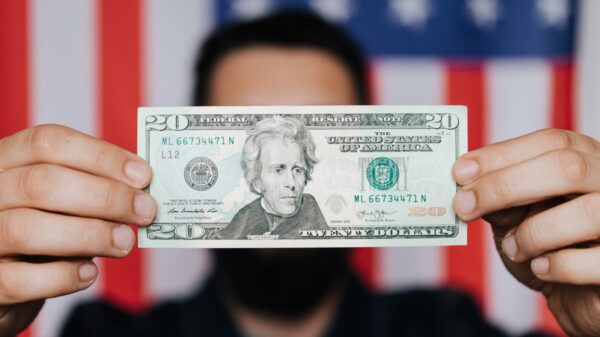 A man holding a $20 bill in front of an American flag.