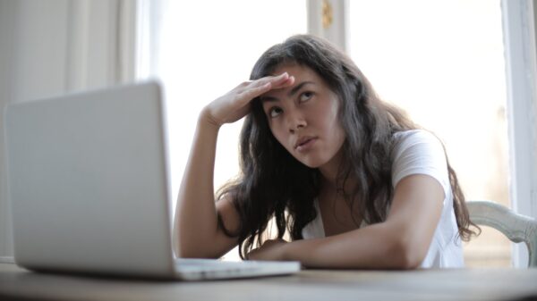 A woman in front of a laptop looking annoyed.