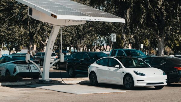 A Tesla charging under a solar panel.