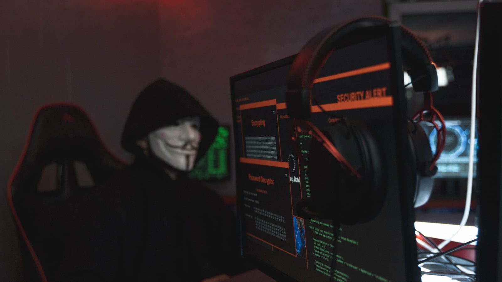 A person in a black hoodie hacking into a computer.