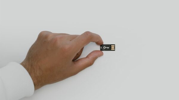 A hand holding a USB drive with a key on it.