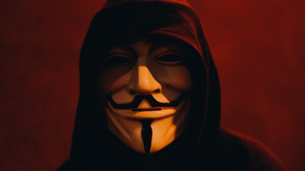 A person in a black hoodie wearing a Guy Fawkes mask.