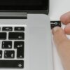 A person inserting a USB drive into a laptop.