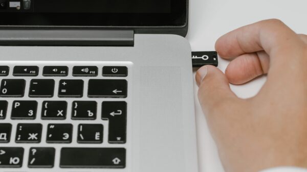 A person inserting a USB drive into a laptop.