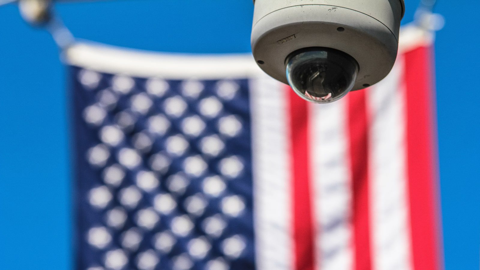 A security camera in front of an American flag.